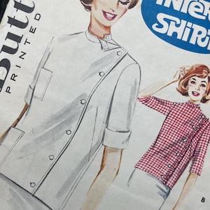 May include: A vintage Butterick sewing pattern envelope for an Intern Shirt, featuring illustrations of two shirt styles labeled A and B. Style A is a solid white shirt with a side button closure, and style B is a red and white gingham check shirt.