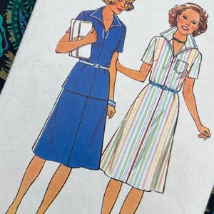 Könnte beinhalten: Ein New Look Maudella Schnittmusterumschlag 6032 für die Größen 10 bis 18. Die Vorderseite zeigt Illustrationen von zwei Kleidern: ein einfarbig blaues Kleid mit weißem Gürtel und ein mehrfarbig vertikal gestreiftes Kleid mit blauem Gürtel.
