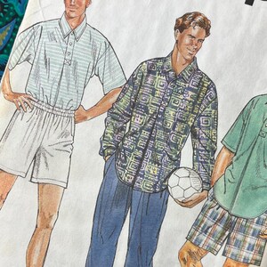 May include: A Simplicity sewing pattern envelope featuring illustrations of three outfits. The first shows a light-coloured polo shirt and shorts. The second shows a long-sleeved patterned shirt and long trousers. The third shows a solid green polo and plaid shorts.