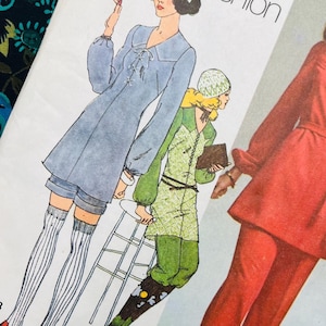 May include: A Simplicity sewing pattern envelope titled Young Contemporary Fashion featuring illustrations of three outfits: a blue tunic with shorts and striped socks, a green patterned tunic with trousers, and a red long-sleeved tunic with matching trousers.