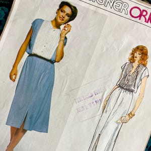 May include: A sewing pattern envelope for a dress labelled Designer Originals 2130 Bellville. The cover features a photograph of a blue dress with a white pleated bodice and a matching illustration of a long white dress with a front slit and button front.