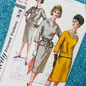 May include: A vintage Simplicity sewing pattern envelope, number 3632, featuring illustrations of three outfits: a grey chevron-patterned two-piece set, a matching grey chevron dress with a tie waist, and a solid yellow two-piece skirt suit.