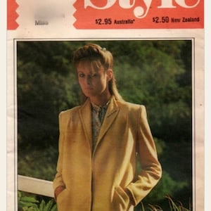 Könnte beinhalten: Vintage Modezeitschrift-Cover mit dem Wort "Style" in Rot. Das Cover zeigt eine Frau in einem hellgelben Blazer, die Hände in den Taschen, vor einem verschwommenen grünen Hintergrund. Die Nummer 3269 ist oben.
