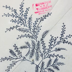 May include: Close-up of a white fabric with a dark blue botanical design. The design features a detailed illustration of leaves and berries. The text "BOYNTON - & - TURNER'S SUPERIOR TRIMMINGS" is stamped in red.