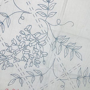 May include: A white fabric transfer pattern featuring blue ink outlines of wisteria flowers and leafy vines. The design includes dashed lines forming a grid pattern across the surface and the text W.2668 printed in the upper right corner.
