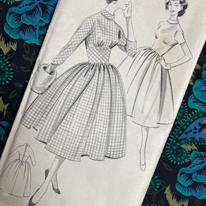 May include: A vintage sewing pattern envelope featuring two illustrations of dresses with full skirts and fitted bodices. One dress has long sleeves and a checkered pattern, while the other has short sleeves. The text reads WELDONS LIMITED. 113-114 FLEET STREET.
