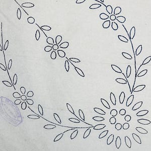 Könnte beinhalten: Ein weißer Stoffbogen mit einem dunkelblauen Tintentransfermuster aus einem Blumenkranz und einem separaten Blumenzweig. Ein violetter kreisförmiger Stempel mit dem Text DEIGHTON'S ist unten links auf der Stoffoberfläche zu sehen.