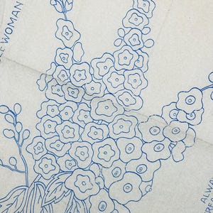 May include: A light beige paper sheet featuring a blue ink line drawing of a cluster of flowers with rounded petals and leaves. The text "WOMAN' SEPT" is visible in the upper left corner, and "ALWAY" and "ANCHOR THRE" are printed in the lower right.