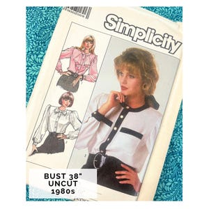 Può includere: Un modello di cucito Simplicity vintage con disegni di camicette. Il modello mostra illustrazioni di camicette con dettagli come volant, fiocchi e finiture a contrasto. Il testo sul modello recita "BUST 38" UNCUT 1980s".