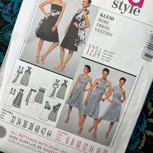 May include: A Burda Style sewing pattern featuring dress designs. The cover displays images of women in various dresses, with text in multiple languages including "KLEID", "ROBE", and "DRESS". Sizes are listed in both US and European measurements.