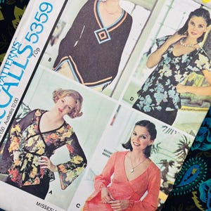 May include: A McCall's 5359 sewing pattern envelope for a misses' set of blouses. The cover features four illustrations of blouses with varying necklines, sleeve lengths, and floral or solid fabric designs, labeled A, B, C, and D.