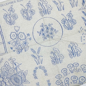 May include: A light grey paper sheet featuring blue ink illustrations of various wildflowers, wheat stalks, and floral arrangements. The text "WITH THE DECEMBER 193" is visible in the upper left corner. The paper has visible fold lines throughout.