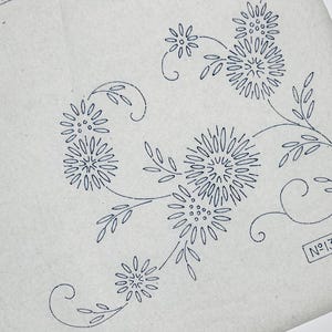 May include: A light grey iron-on embroidery transfer sheet featuring a dark blue floral pattern of multiple daisy-like flowers with curved stems and leaves. The text "No 13961" is printed in a rectangular box in the lower right corner of the sheet.