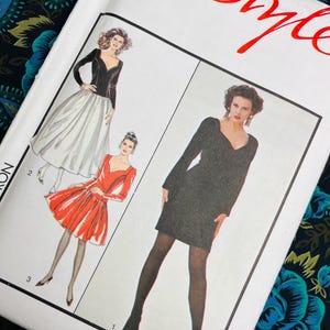May include: A vintage sewing pattern featuring illustrations of three different dress designs. The dresses include a black dress, a red dress, and a black and white dress. The word "Style" is written in red script at the top.