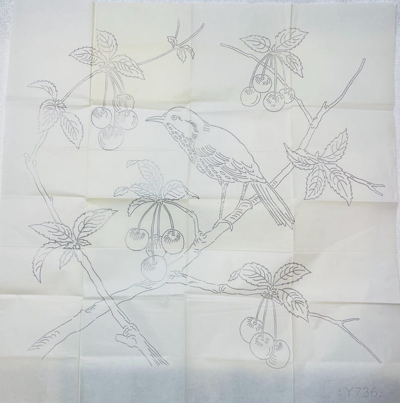 Puede incluir: Un dibujo lineal detallado de un p&aacute;jaro posado en una rama con cerezas y hojas. El dise&ntilde;o est&aacute; sobre un papel cuadrado blanquecino con pliegues visibles. El p&aacute;jaro mira hacia la izquierda, con intrincados detalles de plumas y ramas.