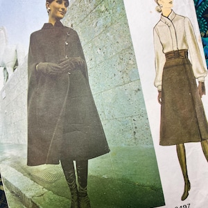 May include: A vintage sewing pattern envelope labeled 2497 and GALITZINE. The front features a photograph of a dark cape, hat, and boots, alongside a fashion illustration of a cream-colored blouse with a high collar and a brown skirt.