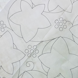 Puede incluir: Primer plano de un papel blanco con un diseño de contorno floral negro. El diseño presenta hojas grandes en forma de estrella de cinco puntas y grupos de pequeños círculos, posiblemente representando bayas. El patrón se repite en el papel.