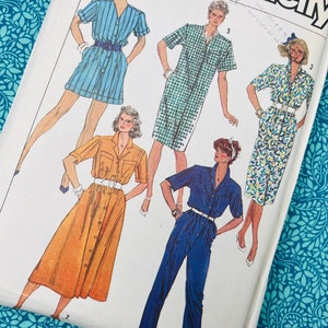 Pode incluir: Um padrão de costura Simplicity vintage com ilustrações de designs de roupas femininas. Os designs incluem um macacão listrado azul, um vestido xadrez verde, um vestido com estampa floral, um vestido abotoado laranja e um macacão azul. O padrão está em um fundo branco.