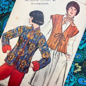 May include: A vintage sewing pattern envelope featuring illustrations of two outfits. One figure wears a blue floral jacket with red cuffs and red trousers. The other wears an orange vest over a white blouse and skirt. Text reads: LIBERTY & CO REGRET THAT PAPER PATTERNS CANNOT BE EXCHANGED.