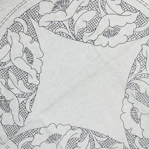 May include: A white paper embroidery transfer pattern featuring four circular floral motifs with cross-hatched shading. The design includes black line art of flowers and leaves. Text in the corner reads: 'ht on dark/dark on light mat before proceeding' and 'NSF Bolton'.