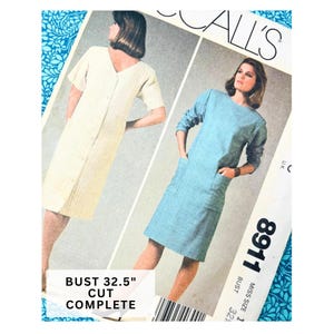 Pode incluir: Padrão de costura vintage da McCall's com dois modelos de vestidos. Um vestido é amarelo claro com botões na frente, o outro é azul claro com bolsos. O padrão inclui o texto "BUST 32.5" e "CUT COMPLETE".