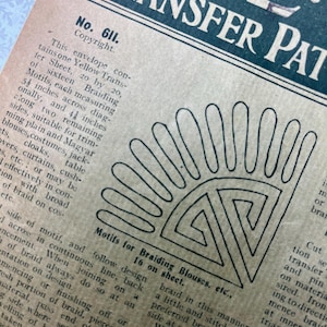 May include: A vintage paper transfer pattern envelope labeled No. 611, featuring a printed black line drawing of a fan-shaped motif with geometric details. The text describes sixteen braiding motifs measuring 5.25 inches by 4.25 inches on a sheet.