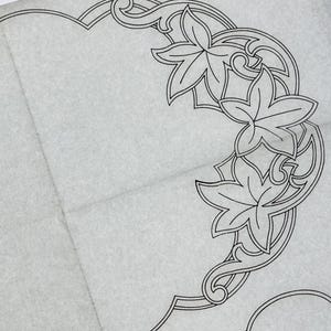 May include: A light grey fabric piece featuring a dark black line art pattern of stylised ivy leaves arranged in a circular border. The design includes intricate scrollwork and leaf motifs that repeat across the surface of the textile material.