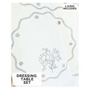 Könnte beinhalten: Weißes Schminktisch-Set mit gewelltem Rand und floraler Stickerei. Das Set enthält zwei Größen. Der Text "DRESSING TABLE SET" ist unten links aufgedruckt.