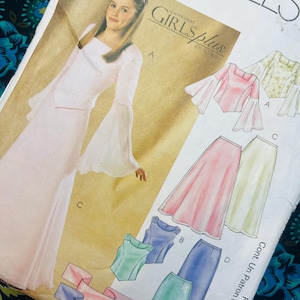 Puede incluir: Un sobre de patrón de costura McCall's para tallas Girls Plus 10 1/2 a 16 1/2. La portada presenta ilustraciones de una blusa de manga larga acampanada y una falda larga en varios colores, incluyendo rosa, verde, azul y blanco.