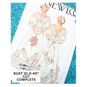 May include: Vintage sewing pattern featuring illustrations of two women in wedding dresses. The dresses are ivory with lace and bow details. The text on the pattern reads "BUST 31.5-40" CUT COMPLETE".