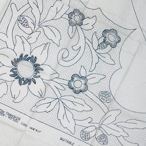 Pode incluir: Uma folha de tecido branco com um padrão de transferência de bordado em tinta azul escura de flores grandes, folhas e botões. O texto diz STRANDED COTTON TRANSFER, N P488, SIZES - 43" SQU COSY 14" X 12" e SUITABLE. O design inclui sombreamento pontilhado.