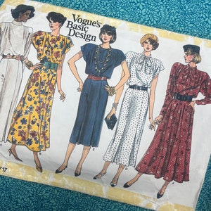 Peut inclure: Patron de couture Vogue's Basic Design avec des illustrations de cinq robes différentes. Les robes sont de différentes couleurs et motifs, notamment des motifs floraux, à pois et unis. Le patron est sur fond blanc avec le texte "Vogue's Basic Design".