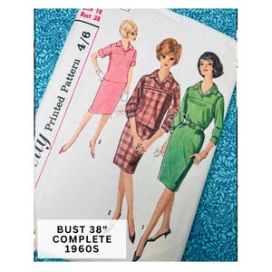 May include: A vintage sewing pattern envelope featuring illustrations of three outfits: a pink two-piece set, a red plaid skirt suit, and a green dress. The text reads "Size 18 Bust 38", "Printed Pattern 4/6", and "Bust 38" Complete 1960s" on the white paper.