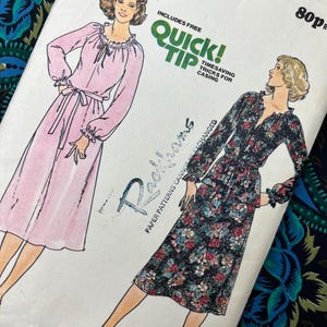 May include: A vintage sewing pattern with illustrations of two dresses. One is pink with a tie waist, the other black with a floral print. The pattern includes the text "Fast & Easy" and "Quick Tip".