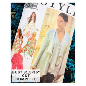 Puede incluir: Un patrón de costura con ilustraciones de prendas de vestir para mujer, incluyendo una chaqueta larga blanca y tops florales. El patrón incluye el texto "CONTORNO DE BUSTO 80-91cm" y está "COMPLETO". El fondo presenta una tela floral.