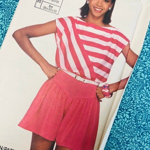 Può includere: Un modello di cucito vintage con una donna che indossa un completo a due pezzi. La parte superiore ha strisce rosse e bianche, e i pantaloncini sono rossi a tinta unita. Il numero del modello è 7395, con taglie USA ed europee.