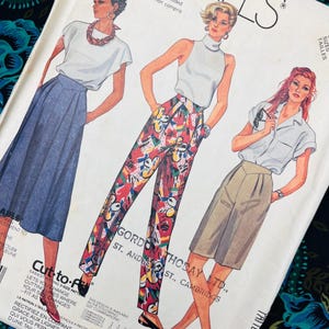 Puede incluir: Un sobre de patrón de costura McCall's con ilustraciones de tres conjuntos: una falda con una blusa de manga corta, pantalones de talle alto con un estampado floral abstracto colorido y cuello alto sin mangas, y pantalones cortos hasta la rodilla.
