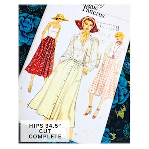 May include: A Vogue Patterns sewing pattern envelope featuring three illustrations of outfits with skirts and blouses. The text on the envelope reads Vogue Patterns and HIPS 34.5" CUT COMPLETE. The illustrations show various skirt styles including floral, solid, and checkered patterns.