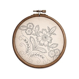 K&ouml;nnte beinhalten: Ein runder h&ouml;lzerner Stickrahmen mit einem cremefarbenen Stoff mit einem schwarzen Blumenmuster. Das Design zeigt Blumen, Bl&auml;tter und Stiele mit detaillierten Umrissen. Der Holzrahmen hat einen messingfarbenen Spannmechanismus.