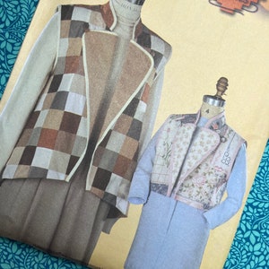 Op de afbeelding: Een naaipatroon met twee paspoppen met gewatteerde vesten. Eén vest heeft een patchwork-ontwerp in bruine, beige en grijze vierkanten. Het andere vest heeft een bloemen- en patchwork-ontwerp. Het patroon staat op een crèmekleurige achtergrond.