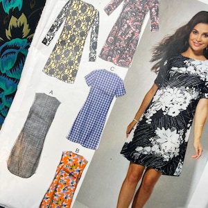 May include: A sewing pattern envelope featuring illustrations of five dress variations labelled A, B, C, E, and F. The designs include a solid grey shift, an orange floral print, a blue grid pattern, a pink floral print, and a yellow lace overlay.