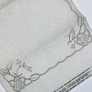 Könnte beinhalten: Ein durchscheinender Bogen Deighton's Transfers mit einem floralen Randdesign in schwarzer Linienführung und gewelltem Rand. Der Text lautet: SILVER TRANSFERS will transfer light on dark material dark on light material DEIGHTON'S TRANSFERS.