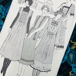 May include: A white paper sewing pattern envelope labelled Realm Special Pattern Size 12. The front features black and white line illustrations of four different dress styles, including variations with long sleeves, patterned skirts, and decorative trim.