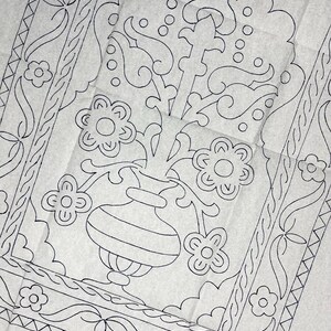 Puede incluir: Un patrón de papel blanco con un dibujo de líneas negras de un jarrón central lleno de flores estilizadas. El diseño está enmarcado por un borde decorativo con motivos florales repetitivos y líneas geométricas, impreso en una hoja fina y arrugada.