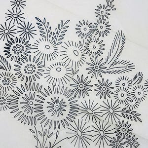 Könnte beinhalten: Ein weißer Stoff mit einem schwarzen Linienstickmuster, das einen großen Blumenstrauß darstellt. Das Design besteht aus mehreren gänseblümchenartigen Blumen mit strahlenden Blütenblättern und verschiedenen Blattformen. Der Text WEBBER ist am unteren Rand sichtbar.