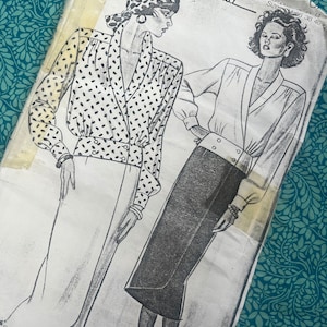 May include: A vintage New Look Maudella sewing pattern. The illustration shows two women in 1980s fashion, one in a polka-dot blouse and skirt, the other in a plain blouse and skirt. The pattern is on a white background.