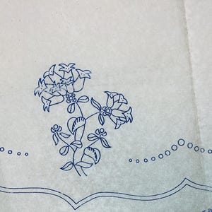 Puede incluir: Un letrero de madera hecho a mano con el texto "Bienvenido a nuestro hogar" en un estilo manuscrito. El letrero está pintado de blanco con un acabado envejecido y un borde marrón oscuro. Un pequeño corazón decorativo está adjunto en la parte inferior.