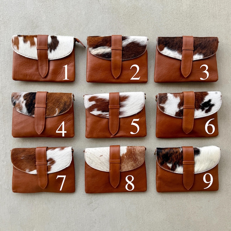 May include: Nine brown leather clutch bags with cowhide flap closures. Each bag has a different pattern of brown, black, and white cowhide. The bags are numbered 1 to 9.