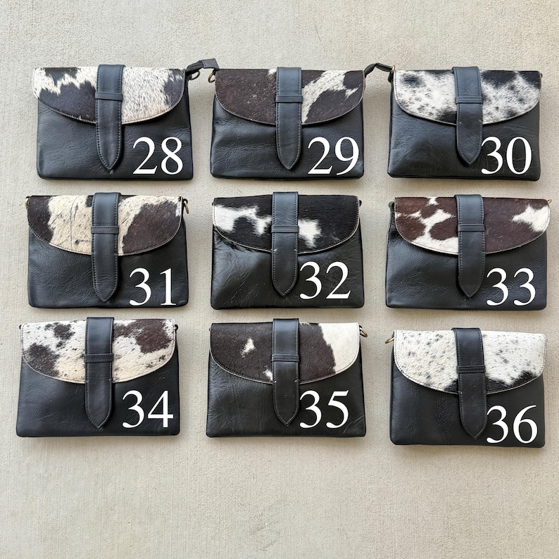 May include: Nine black leather crossbody bags with cowhide flap closures. Each bag has a black leather strap and a buckle closure. Numbers 28 to 36 are printed on the bags in white.