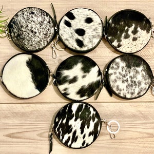 May include: Seven round black and white cowhide coin purses with silver keychains.